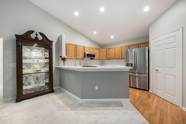 4219 Inverness St Unit 118, Dexter, MI 48130 - kitchen with stainless steel appliances, light countertops, a peninsula, lofted ceiling, and brown cabinetry