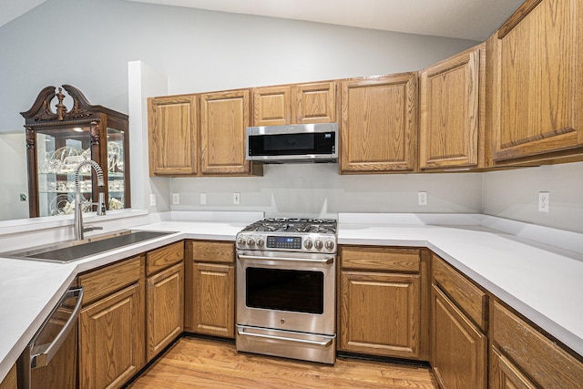 4219 Inverness St Unit 118, Dexter, MI 48130 - kitchen with stainless steel appliances, lofted ceiling, light wood-style floors, light countertops, and brown cabinetry