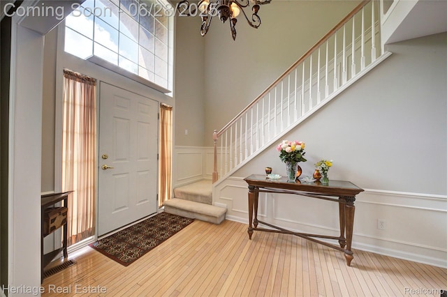 3400 Yosemite Dr, Lake Orion, MI 48360 - entrance foyer featuring stairway, hardwood / wood-style floors, a chandelier, a wainscoted wall, and a decorative wall