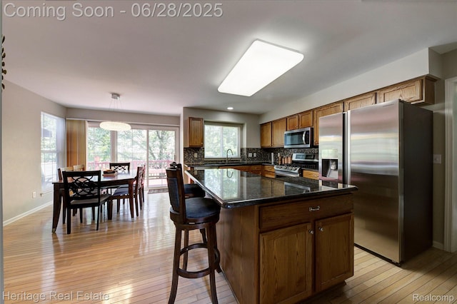 3400 Yosemite Dr, Lake Orion, MI 48360 - kitchen featuring stainless steel appliances, light wood-style floors, backsplash, brown cabinetry, and a center island