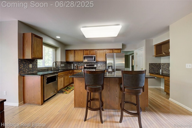 3400 Yosemite Dr, Lake Orion, MI 48360 - kitchen featuring stainless steel appliances, light wood-style flooring, decorative backsplash, a center island, and a kitchen bar