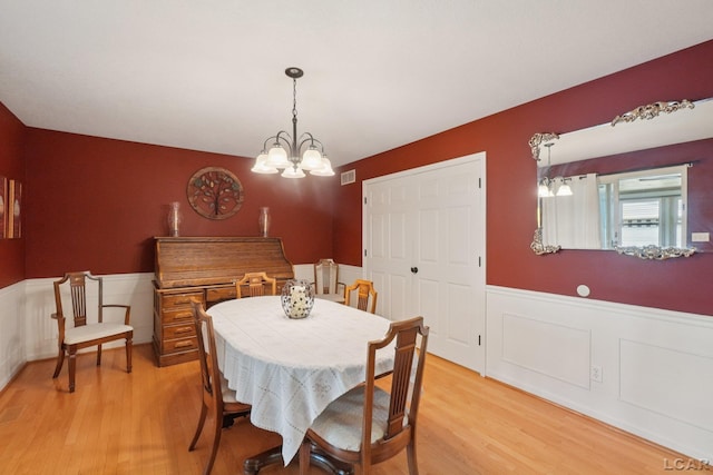 221 Burt St, Tecumseh, MI 49286 - dining room featuring a wainscoted wall, light wood-style floors, a chandelier, and a decorative wall