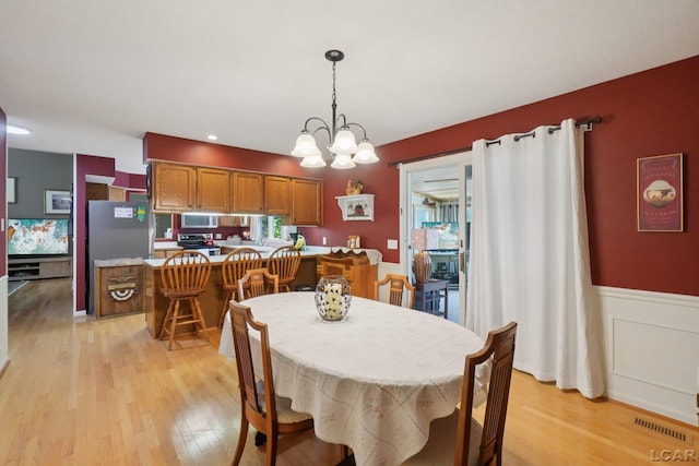 221 Burt St, Tecumseh, MI 49286 - dining space with light wood finished floors, a chandelier, and a wainscoted wall
