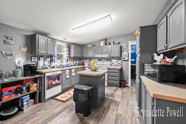 17122 Kent Ave, Morley, MI 49336 - kitchen with black microwave, white range oven, gray cabinetry, lofted ceiling, and light wood-style flooring