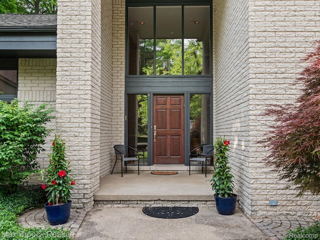 6224 Bromley Ct, West Bloomfield, MI 48322 - view of exterior entry featuring brick siding, covered porch, and roof with shingles