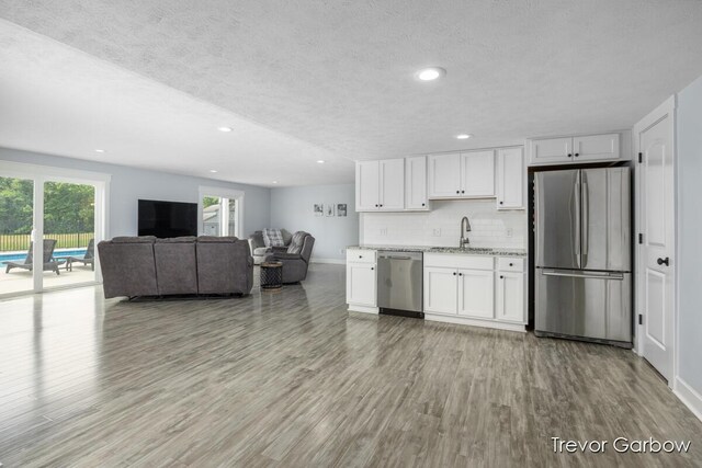 6770 Rivers Edge Ln, Middleville, MI 49333 - kitchen with appliances with stainless steel finishes, light wood finished floors, white cabinetry, backsplash, and light stone counters