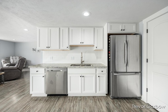 6770 Rivers Edge Ln, Middleville, MI 49333 - kitchen featuring stainless steel appliances, a textured ceiling, light stone countertops, light wood-style flooring, and white cabinetry