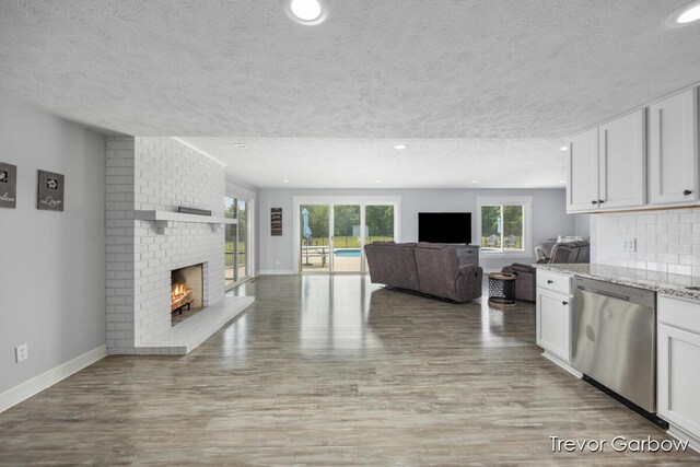 6770 Rivers Edge Ln, Middleville, MI 49333 - kitchen featuring dishwasher, a textured ceiling, open floor plan, healthy amount of natural light, and a fireplace