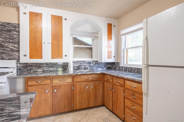 785 Kenilworth Ave, Pontiac, MI 48340 - kitchen featuring white appliances, dark stone counters, light tile patterned floors, brown cabinetry, and backsplash