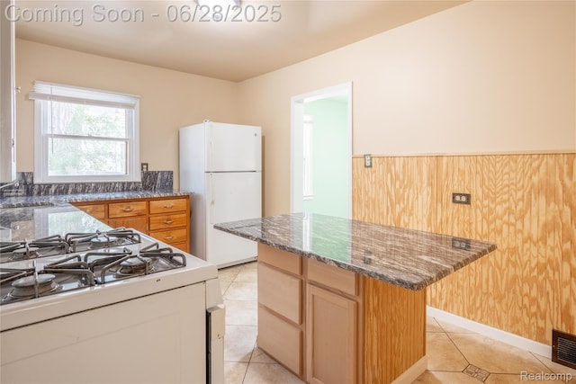 785 Kenilworth Ave, Pontiac, MI 48340 - kitchen featuring white appliances, a center island, light tile patterned flooring, and dark stone countertops