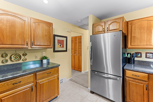 525 Langfield St, Northville, MI 48167 - kitchen with freestanding refrigerator, brown cabinetry, light tile patterned floors, and light colored carpet