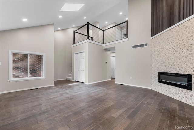 24790 Ashley Ct, Redford, MI 48239 - unfurnished living room featuring high vaulted ceiling, a skylight, wood finished floors, a glass covered fireplace, and recessed lighting