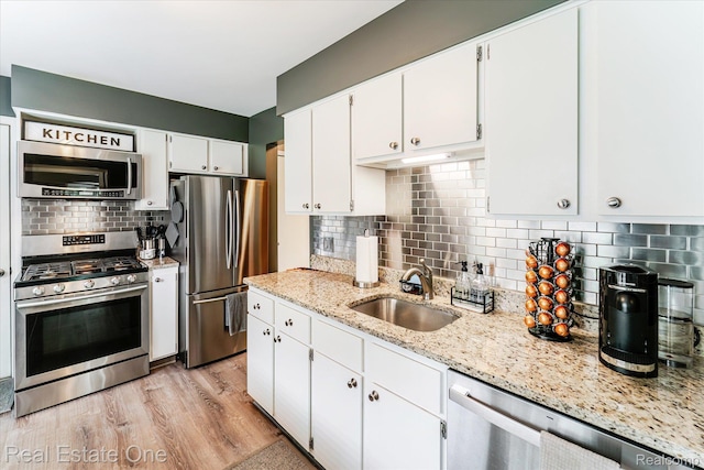 1106 Kings Cove Dr Unit 355, Rochester, MI 48306 - kitchen with appliances with stainless steel finishes, backsplash, white cabinets, light wood-style flooring, and light stone counters