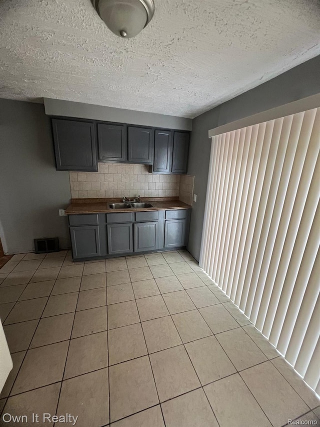 8620 Fielding St, Detroit, MI 48228 - kitchen with wood counters, backsplash, light tile patterned floors, a textured ceiling, and gray cabinetry