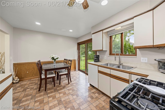 3123 W Utica Rd, Shelby Twp, MI 48317 - kitchen with black range with gas stovetop, white cabinets, light countertops, a wainscoted wall, and ceiling fan