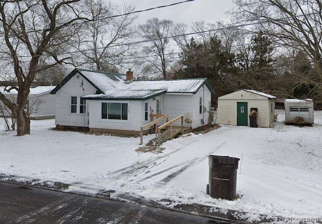 1008 Henderson St, Big Rapids, MI 49307 - view of front of home featuring a shed, a chimney, and a metal roof