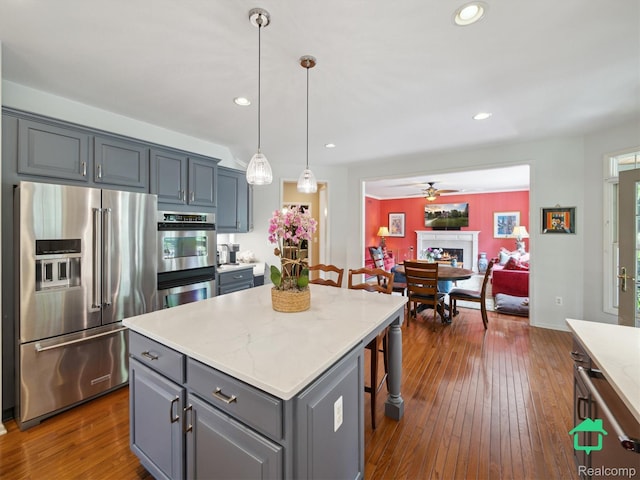 6345 Brookview Dr, Saline, MI 48176 - kitchen featuring appliances with stainless steel finishes, gray cabinets, a ceiling fan, a breakfast bar area, and dark wood-style flooring