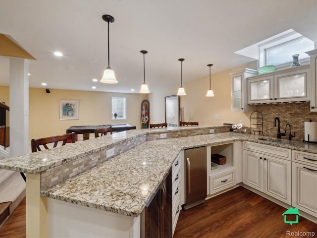 6345 Brookview Dr, Saline, MI 48176 - kitchen featuring cream cabinetry, dark wood-style floors, a kitchen bar, glass insert cabinets, and a peninsula