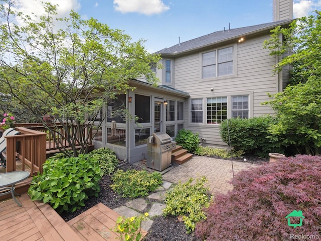 6345 Brookview Dr, Saline, MI 48176 - rear view of house featuring a sunroom, a wooden deck, a chimney, and a patio
