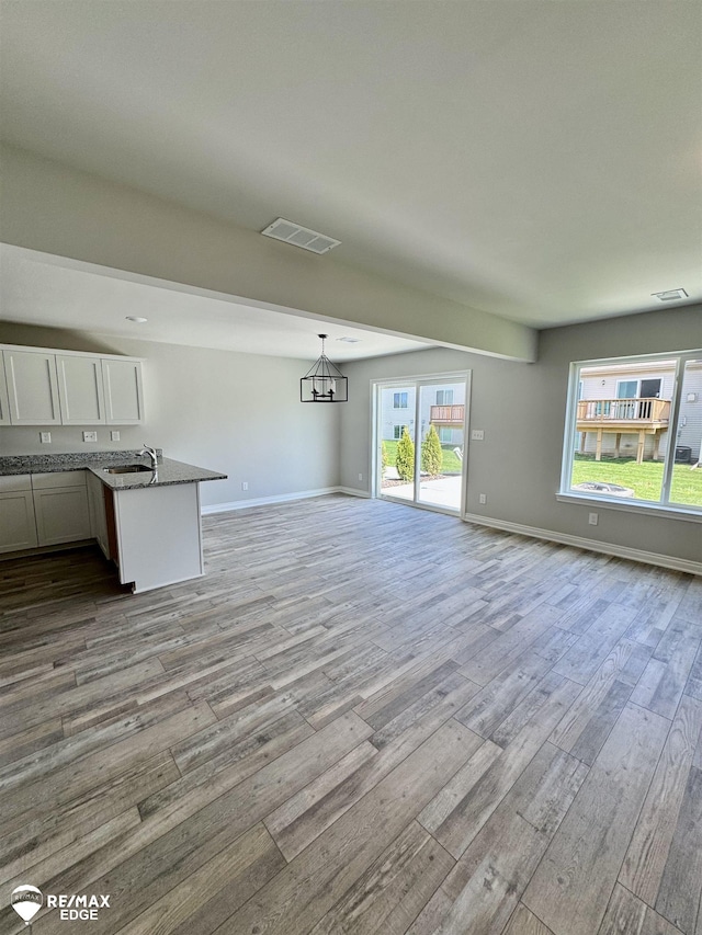 31007 Gregory St, Grand Blanc, MI 48439 - unfurnished living room featuring wood finished floors and a chandelier