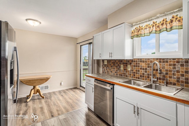1006 Southlawn Ave, Flint, MI 48507 - kitchen with appliances with stainless steel finishes, decorative backsplash, wood finished floors, and white cabinets