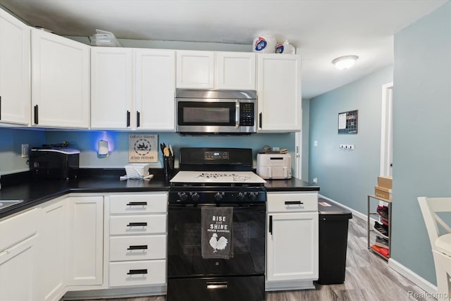 759 Elm St, Allenton, MI 48002 - kitchen with black range with gas stovetop, stainless steel microwave, white cabinets, dark countertops, and light wood-style flooring