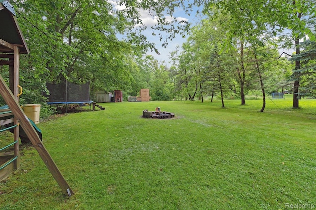 759 Elm St, Allenton, MI 48002 - view of green lawn with a trampoline, a fire pit, and a storage shed