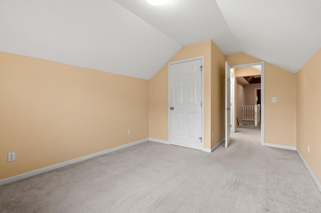 220 Deer Path Ln, Battle Creek, MI 49015 - additional living space with light colored carpet, vaulted ceiling, and a textured ceiling
