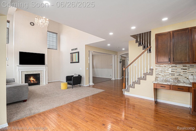 27455 Harrington Way, Novi, MI 48374 - unfurnished living room with stairs, light wood-style flooring, a fireplace with flush hearth, recessed lighting, and a chandelier