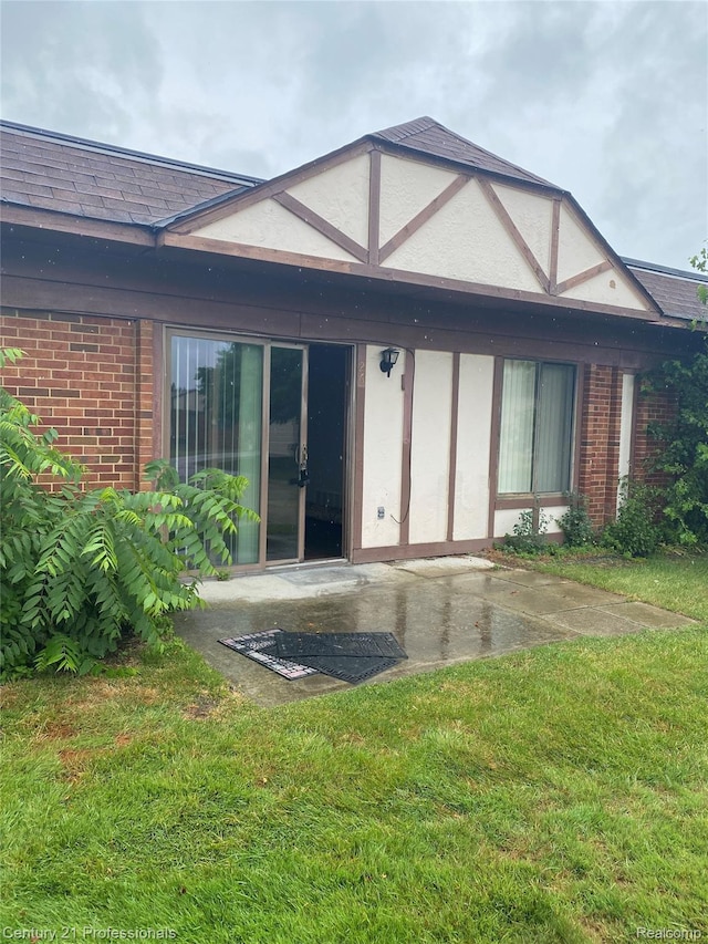 29900 N Grand Oaks Dr Unit 26, Warren, MI 48092 - rear view of house featuring brick siding, a patio, a lawn, and roof with shingles