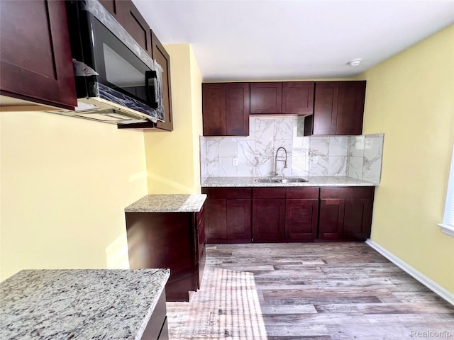 23657 Hill Ave, Warren, MI 48091 - kitchen with stainless steel microwave, light wood-style flooring, tasteful backsplash, and light stone countertops