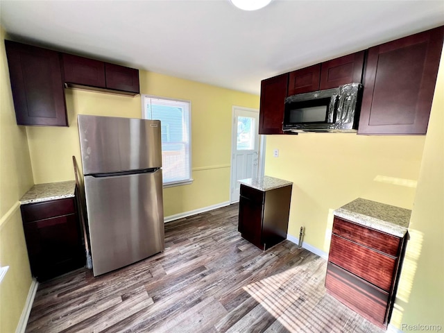 23657 Hill Ave, Warren, MI 48091 - kitchen with freestanding refrigerator, dark wood-style floors, light stone counters, and reddish brown cabinets