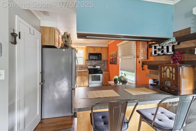 8025 Mayfair St, Taylor, MI 48180 - kitchen featuring appliances with stainless steel finishes, ornamental molding, backsplash, wood finished floors, and a peninsula