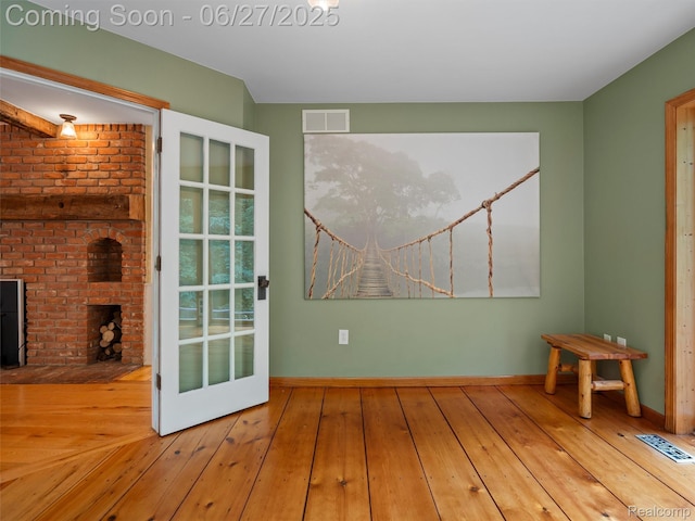 9767 Whisperwood Ln, Brighton, MI 48116 - spare room featuring wood-type flooring and a fireplace