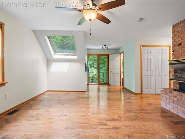 9767 Whisperwood Ln, Brighton, MI 48116 - unfurnished living room with a skylight, a fireplace, wood finished floors, and a ceiling fan