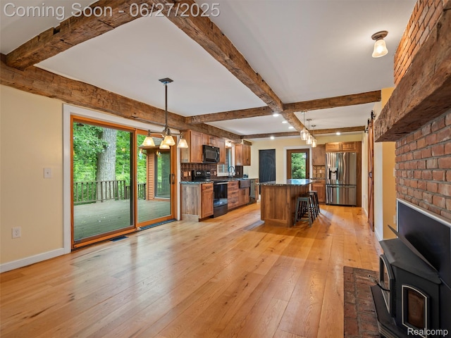 9767 Whisperwood Ln, Brighton, MI 48116 - kitchen with black appliances, dark countertops, a wood stove, light wood-style flooring, and plenty of natural light