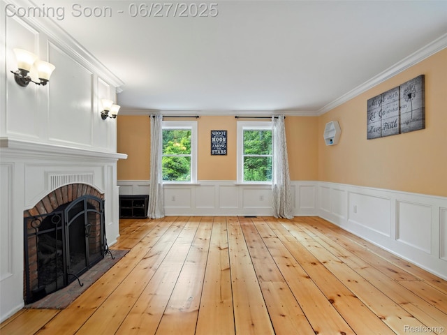 9767 Whisperwood Ln, Brighton, MI 48116 - unfurnished living room featuring a brick fireplace, hardwood / wood-style flooring, ornamental molding, and wainscoting