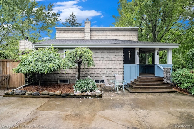 6428 W Court St, Flint, MI 48532 - view of front of property featuring a chimney, a shingled roof, and a patio area