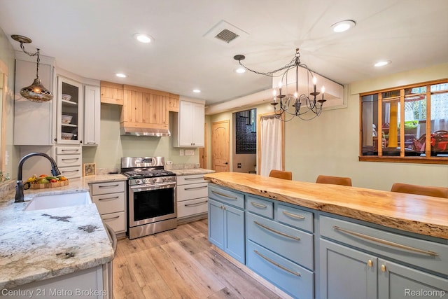 6428 W Court St, Flint, MI 48532 - kitchen with stainless steel gas stove, under cabinet range hood, light wood-style flooring, a chandelier, and recessed lighting