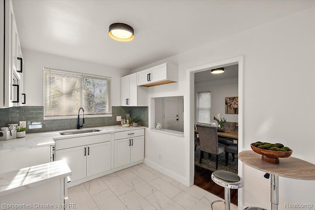16573 Griggs St, Detroit, MI 48221 - kitchen with light marble finish flooring, white cabinetry, decorative backsplash, and light stone counters