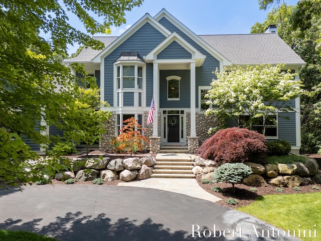 1977 Emerald Glen Ct NE, Ada, MI 49301 - view of front of house with stone siding, a chimney, and a shingled roof