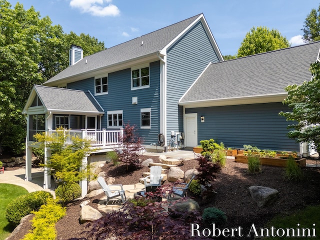 1977 Emerald Glen Ct NE, Ada, MI 49301 - back of property featuring a patio area, a sunroom, a chimney, and a shingled roof