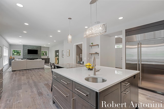 1977 Emerald Glen Ct NE, Ada, MI 49301 - kitchen featuring stainless steel built in fridge, recessed lighting, light wood-style floors, decorative light fixtures, and a center island with sink