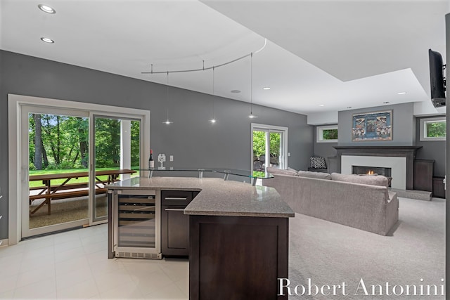 1977 Emerald Glen Ct NE, Ada, MI 49301 - kitchen with beverage cooler, light stone countertops, dark brown cabinets, a warm lit fireplace, and recessed lighting