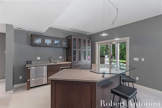 1977 Emerald Glen Ct NE, Ada, MI 49301 - kitchen featuring glass insert cabinets, stainless steel dishwasher, a kitchen bar, dark brown cabinetry, and recessed lighting