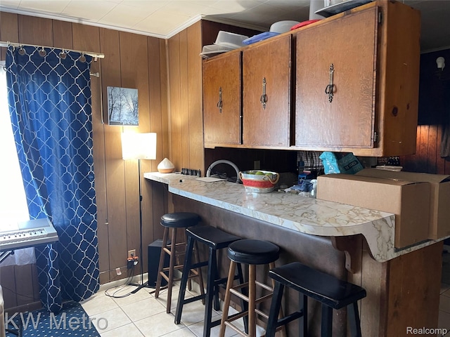 103 N Roselawn St, Pontiac, MI 48342 - kitchen featuring light tile patterned floors, brown cabinetry, crown molding, a breakfast bar area, and light countertops