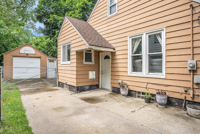 134 Honeoye St SW, Grand Rapids, MI 49548 - view of exterior entry with driveway, a shingled roof, a garage, and a gate