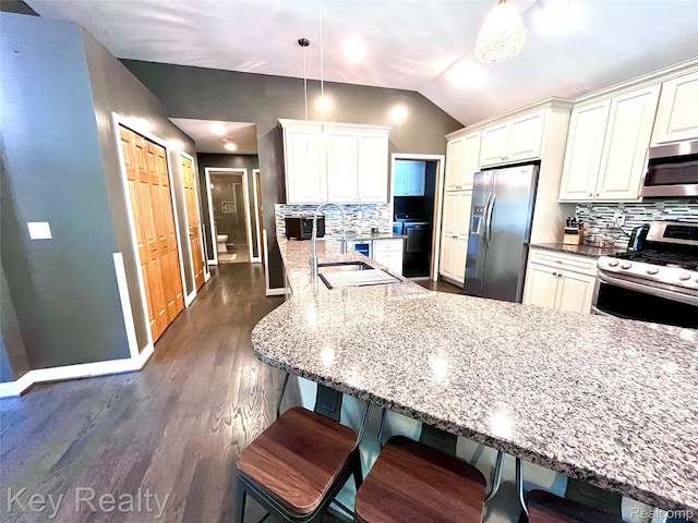 7949 Church Rd, Grosse Ile, MI 48138 - kitchen featuring appliances with stainless steel finishes, light stone counters, backsplash, vaulted ceiling, and dark wood-type flooring