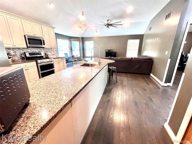 7949 Church Rd, Grosse Ile, MI 48138 - kitchen featuring appliances with stainless steel finishes, cream cabinets, lofted ceiling, ceiling fan, and wood finished floors