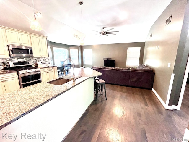 7949 Church Rd, Grosse Ile, MI 48138 - kitchen featuring appliances with stainless steel finishes, cream cabinetry, lofted ceiling, ceiling fan, and dark wood finished floors